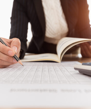 A professional accountant working with financial documents and calculators, ensuring accurate financial management and reporting.