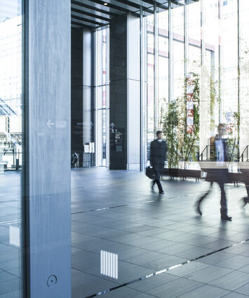 Office building with people coming and going, representing a dynamic workplace environment and professional interactions.
