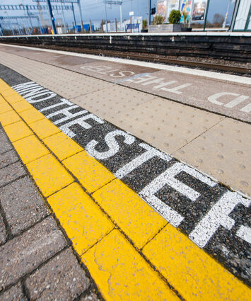 Yellow 'Mind the Step' text line at a British train station, highlighting safety measures for travelers to take while using trains in the United Kingdom.