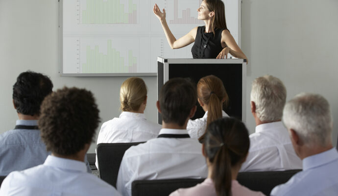 Businesswoman delivering presentation at conference, showcasing expertise and engaging audience in professional setting.